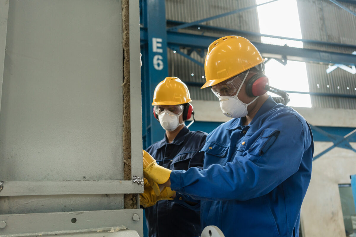 Deux ouvriers portant des équipements de protection lors de l'isolation d'une cuve sous pression industrielle