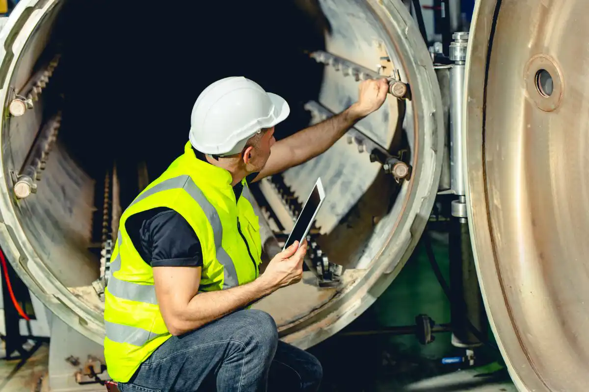 Technicien inspectant une machine industrielle avec une tablette.