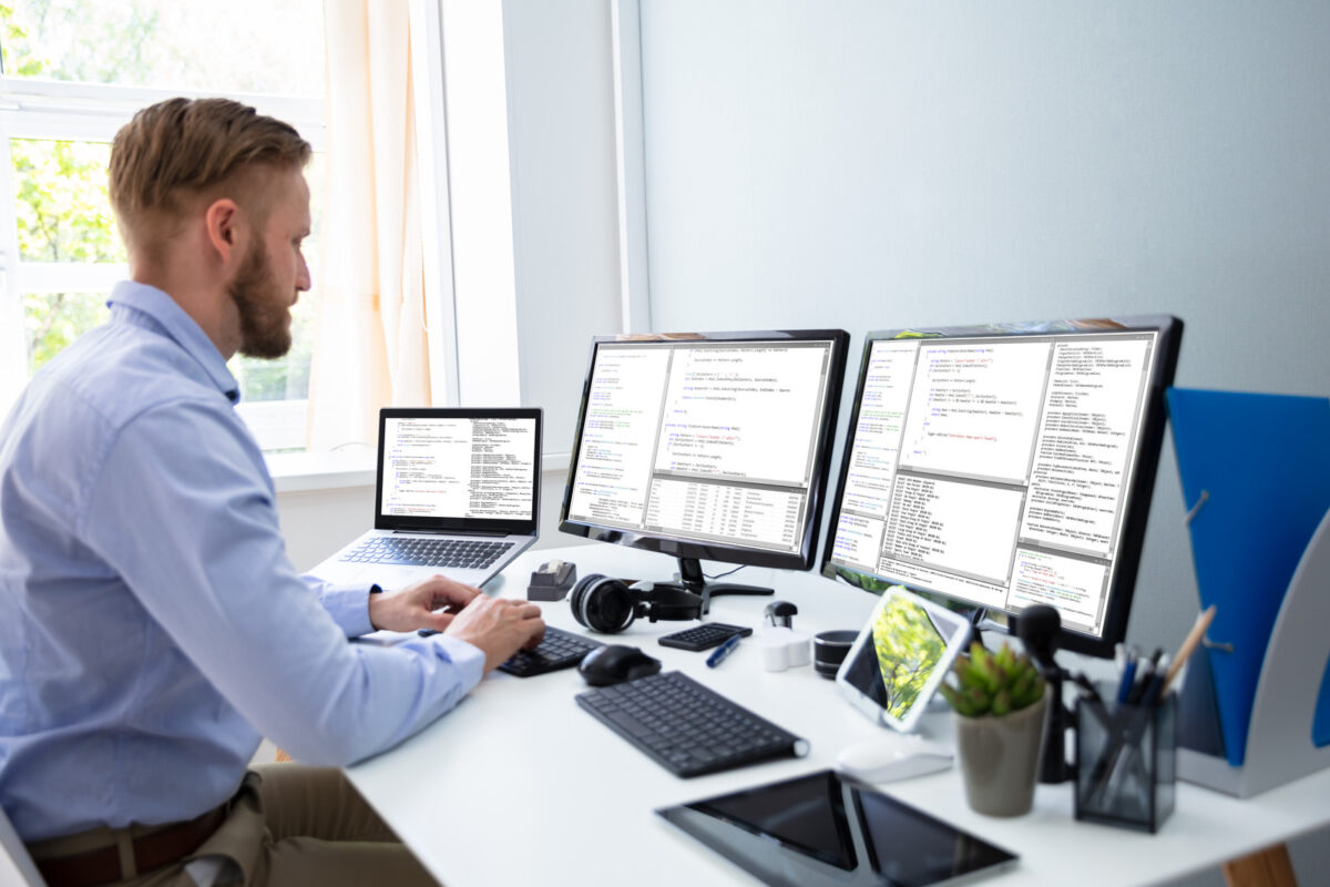 Programmeur informatique écrivant le code d'un programme sur un ordinateur dans un bureau